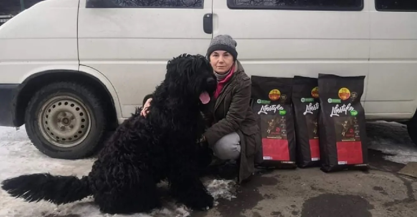 Ukrainos pabėgėlė glosto savo juodakailį didelės veislės šunį, šalia jų Kikos parama Lifestyle pašarai