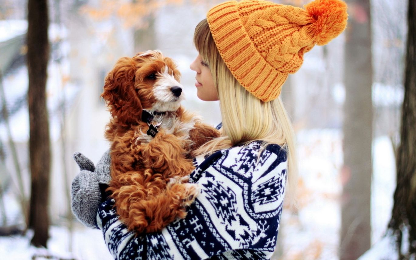 Mergina laikanti šuniuką ant rankų žiemą